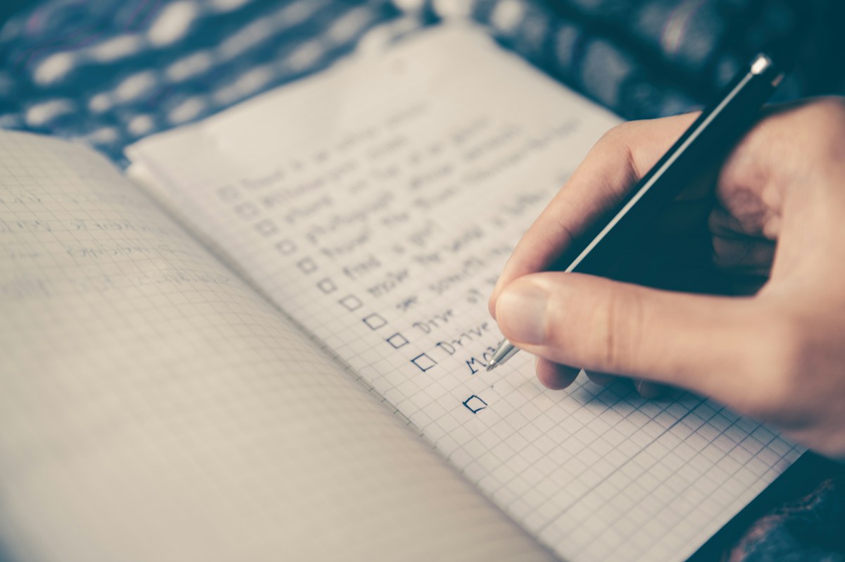 A person writing a careful checklist in a notebook